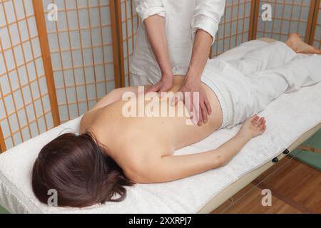 il terapista esegue un massaggio shiatsu sulla schiena di una donna su un tavolo da massaggio Foto Stock