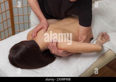 la chiropratica esegue un massaggio sul corpo di una donna su un tavolo terapeutico Foto Stock