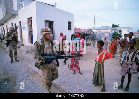 I Marines STATUNITENSI marciano davanti ai bambini somali mentre sono in pattuglia per le strade di Baidoa, Somalia. Foto Stock
