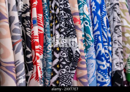 Una fila di vestiti colorati con una varietà di motivi e design Foto Stock