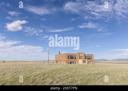 Un edificio scolastico abbandonato in un campo Foto Stock