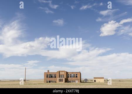Un edificio scolastico abbandonato in un campo panoramico Foto Stock