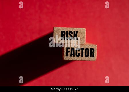 Messaggio sul fattore di rischio scritto su blocchi di legno con sfondo rosso. Simbolo del fattore di rischio concettuale. Copia spazio. Foto Stock