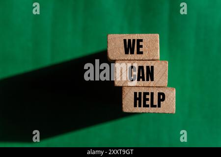 Possiamo aiutare messaggio scritto su blocchi di legno con sfondo verde Foto Stock