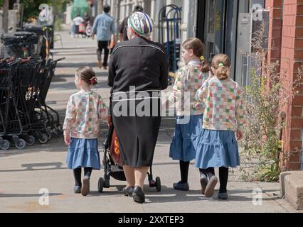 Una madre e le sue tre figlie. Le ragazze indossavano maglioni, gonne e leggings identici. Su Wallabout St. A Williamsburg, Brooklynn, New York. Foto Stock