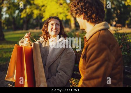 Coppia seduta sulla panchina nel parco dopo lo shopping. Foto Stock