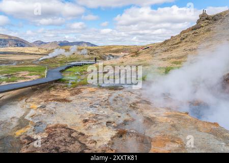 L'area geotermica di Hveradalir in Islanda in una soleggiata giornata primaverile con nuvole e cielo blu Foto Stock