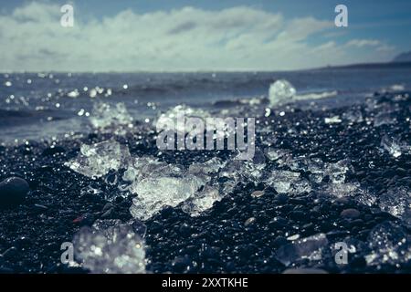 Blocchi di ghiaccio e iceberg rotti su una spiaggia vulcanica di sabbia nera a Diamond Beach in Islanda Foto Stock