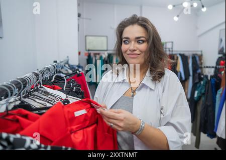 Una donna grassa guarda con orrore al prezzo di un abito in un negozio Plus size. Foto Stock