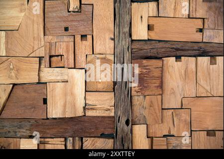 Superficie di fondo in legno astratto con legni irregolari di dimensioni irregolari colori e grani disposti in pattern geometrici casuali alla luce del giorno Foto Stock
