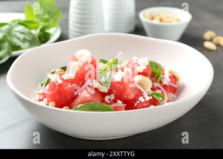 Gustosa insalata con anguria, formaggio feta e basilico sul tavolo nero Foto Stock