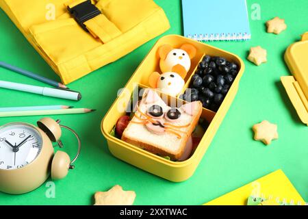 Borsa, pranzo al sacco con spuntini, cancelleria e sveglia sul tavolo verde, primo piano Foto Stock