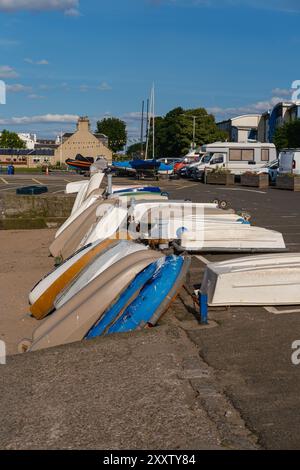 EDIMBURGO - 28 LUGLIO 2024: Una fila di gommoni bianchi, alcuni con scafo blu, sono impilati uno sopra l'altro su una rampa di cemento vicino all'acqua di Fisherrow. Foto Stock