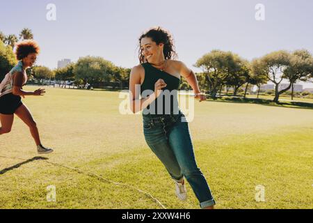 Due energici studenti universitari, migliori amici, giocano a tag e si godono una giornata di sole all'aperto in un parco. Foto Stock