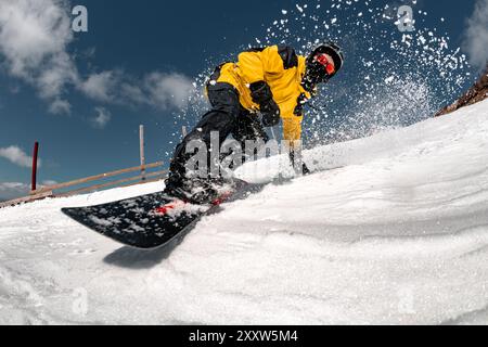 Una foto ravvicinata dello snowboarder è una corsa sulla pista da sci contro il cielo blu e la neve. Concetto di stazione sciistica Foto Stock