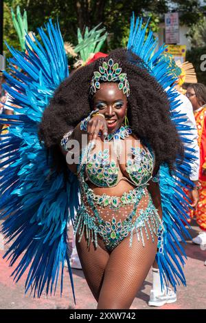 Notting Hill, Londra, Regno Unito. 26 agosto 2024. Il più grande festival di strada d'Europa si svolge nelle strade di Notting Hill. Ballerini esotici a tema giamaicano e gruppi musicali sfilano per le strade, con cibo e intrattenimento di strada intorno alla zona che si aggiungono all'evento. La Grand Parade si svolge il lunedì festivo come il culmine del festival di tre giorni, iniziato nel 1966. Ballerina che si esibisce Foto Stock