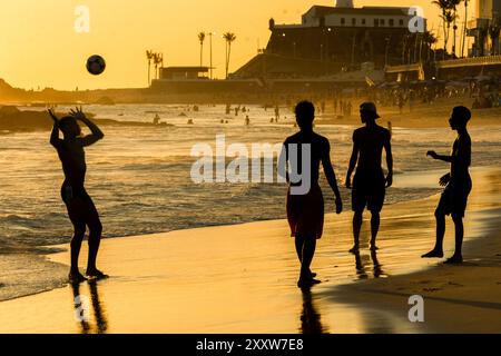 Salvador, Bahia, Brasile - 6 dicembre 2019: Si vedono persone che giocano a Beach Soccer al tramonto sul bordo della spiaggia di Farol da barra. Salvador, Bahia. Foto Stock