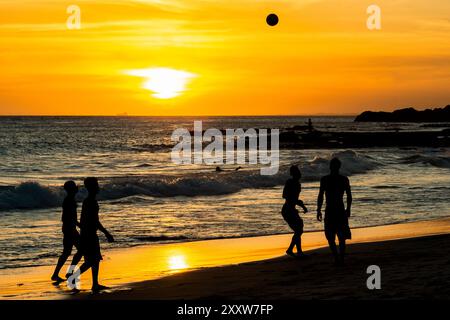 Salvador, Bahia, Brasile - 6 dicembre 2019: Si vedono persone che giocano a Beach Soccer al tramonto sul bordo della spiaggia di Farol da barra. Salvador, Bahia. Foto Stock