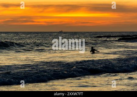 Salvador, Bahia, Brasile - 6 dicembre 2019: I bagnanti si divertono al tramonto sulla spiaggia di Farol da barra nella città di Salvador, Bahia. Foto Stock