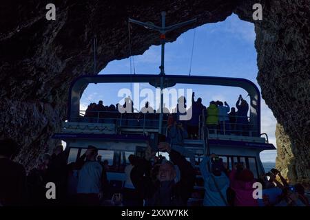 Northland, Bay of Islands, North Island, nuova Zelanda - una nave da crociera passa attraverso l'arco naturale chiamato Hole in the Rock nell'Isola di Piercy Foto Stock