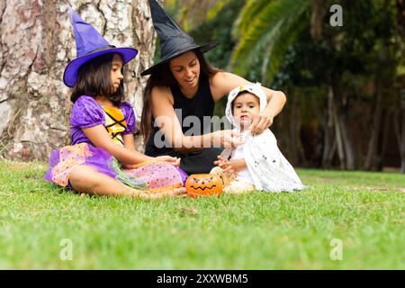 La famiglia vestita da streghe ad halloween seduta in un parco a guardare le caramelle Foto Stock