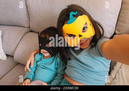 Ragazza che si fa un selfie con suo fratello vestito da Halloween sul divano Foto Stock