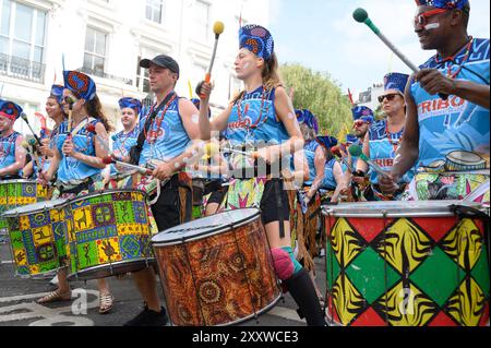 Londra, Regno Unito. 26 agosto 2024. Le persone che si godono il carnevale oggi, a Londra, nel Regno Unito, ma con la tensione dopo le pugnalate di ieri, lasciando tre persone in ospedale. Qui, la musica del Tribo, ispirata alle tribù indigene amazzoniche, i batteristi del Tribo mostreranno autentici ritmi di samba reggae che hanno avuto origine dal movimento dell'orgoglio nero nella città di Salvador de Bahia, intorno al 1969. Crediti: Mary-Lu Bakker/Alamy Live News Foto Stock