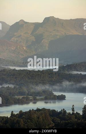 Una splendida vista mattutina attraverso Windermere fino alle spettacolari Langdale Pikes nel Lake District, presa dal punto panoramico di Orrest Head dopo l'alba. Foto Stock