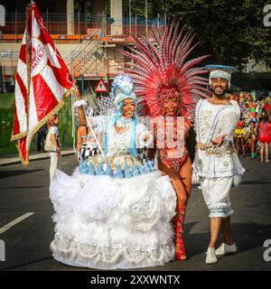 Londra, Regno Unito, 26 agosto 2024. Ballerini anziani, tra cui il principe e la principessa, al fronte del gruppo. I partecipanti alla Paraiso School of Samba, uno dei gruppi più grandi con quasi 200 artisti e musicisti, si recano dalla mattina presto fino all'inizio della processione a mezzogiorno. Il Carnevale di Notting Hill di lunedì vede la principale processione di bande mas, batteristi e gruppi caraibici e sudamericani di salsa, Samba e Soca. I rivelatori celebrano il fine settimana festivo partecipando o guardando lungo il percorso del carnevale, presso impianti audio, bancarelle e luoghi il secondo di due giorni di Foto Stock