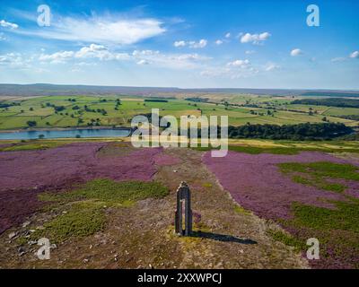 Un drone cattura la vista mozzafiato della torre di avvistamento di Kirkby Malzeard Moor, che mostra l'erica viola. Il Roundhill Reservoir si trova oltre. Foto Stock