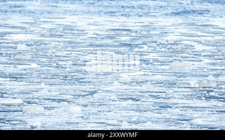 Frammenti di ghiaccio che scioglie e neve bagnata galleggiano sull'acqua di mare, foto di sfondo naturale invernale con messa a fuoco selettiva Foto Stock