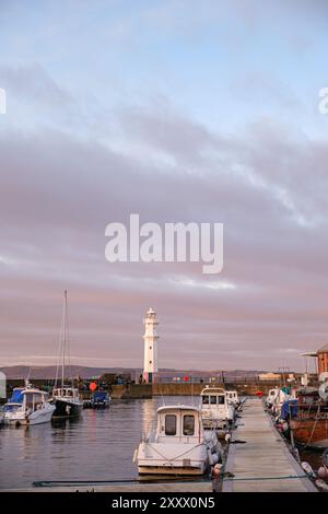 EDIMBURGO - 13 GENNAIO 2024: Il faro si erge alto nel porto di Newhaven a Edimburgo, circondato da barche al tramonto. Foto Stock