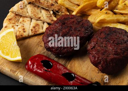 Due polpette di manzo a base di carne macinata con patate fritte, pepe, pita e salsa di yogurt. Foto Stock