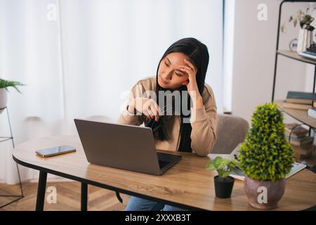 Stanco giovane asiatico coreano donna lavoratore studente fare una breve pausa in lavoro online rimuovere occhiali massaggio dipendente femminile sovraccaricato da laptop Foto Stock