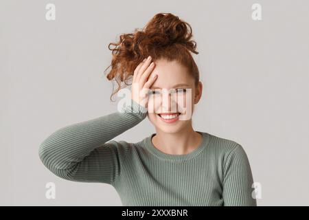 Ritratto di una giovane donna vergognata che copre il viso su sfondo marrone Foto Stock