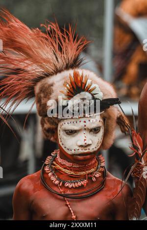 Un uomo della provincia di Hela, Papua nuova Guinea, con vivaci colori per il viso e un suggestivo copricapo adornato di piume, a simboleggiare l'orgoglio tribale. Foto Stock