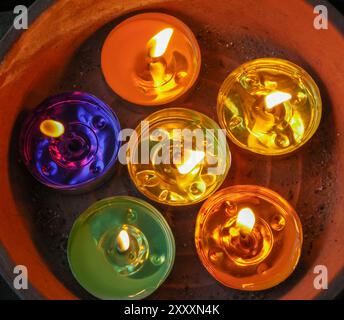 Dettaglio di candele votive colorate in una pentola di terracotta Foto Stock