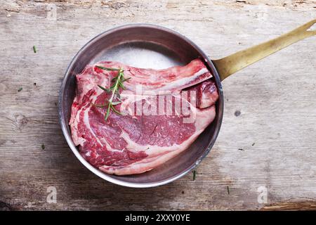 Bistecca cruda con osso a T in una padella di rame Foto Stock