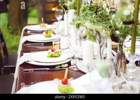 La decorazione della tavola di nozze con vasi di cristallo, fiori e antipasti in stile botanico nel giardino Foto Stock