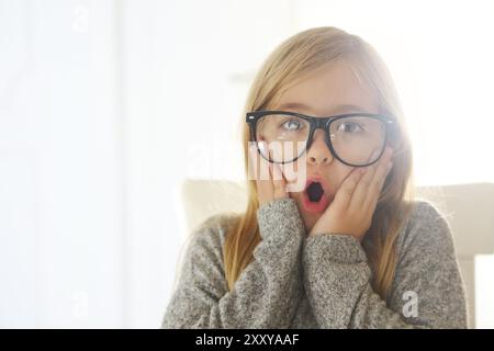 Bambina sorridente con occhiali neri su sfondo bianco. Educazione, scuola, infanzia, persone e concetto di visione Foto Stock