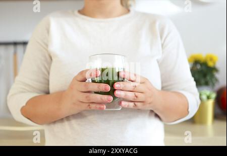 Mani femminili coppa di ritegno di Verde matcha tè sulla cucina. Primo piano Foto Stock