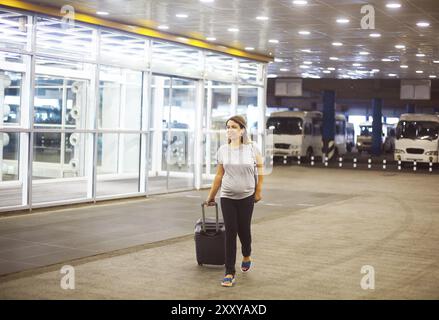 Giovane donna incinta con la valigia in aeroporto o stazione Foto Stock