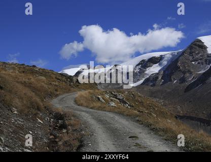 Scena sulla strada per Fluhalp. Strada in ghiaia curva. Ghiacciaio del Findel. Paesaggio a Zermatt Foto Stock