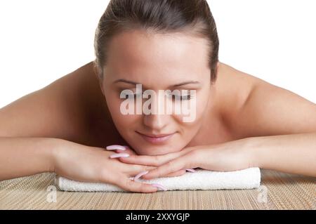 Giovane donna giacente in una spa pronto per ottenere un massaggio, isolato in bianco Foto Stock