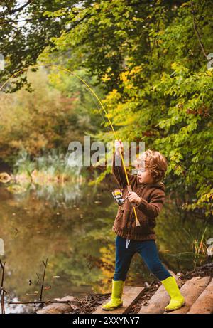 Foto di capretto che tira l'asta mentre pesca il fine settimana. Foto Stock