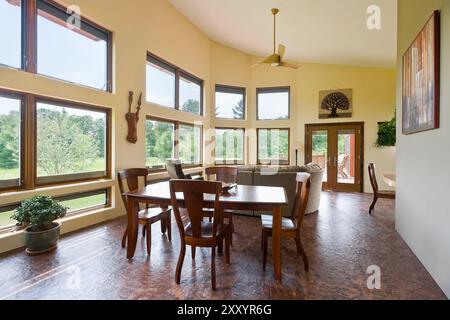 Sala da pranzo e soggiorno combinati con molte finestre nella soleggiata casa solare passiva Foto Stock