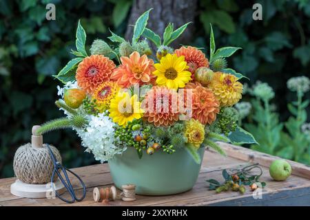 composizione floreale di dalie, girasoli, ortensie, carote selvatiche, cardo, erba, rosa e rami di cespuglio in un vaso rustico Foto Stock