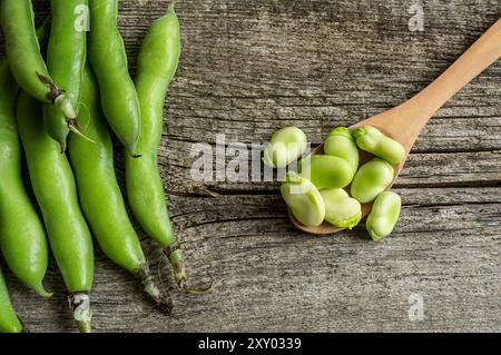 Fave fresche con baccello su fondo rustico, cibo sano Foto Stock