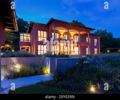 Scena notturna di una grande villa con un grande giardino e tutte le luci accese. Il cielo è limpido, il prato è curato. Nessuno dentro, copia spazio Foto Stock