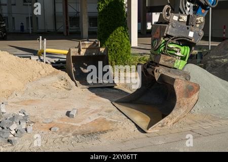 Una grande macchina per l'edilizia è posizionata in un cantiere, pronta per scavare e trasportare ghiaia e sabbia, con materiali da costruzione sparsi intorno. Foto Stock